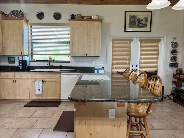 kitchen with white dishwasher, light brown cabinetry, sink, and a breakfast bar area