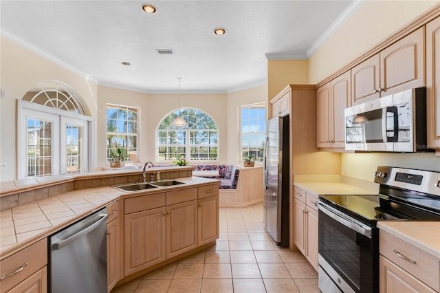 kitchen featuring pendant lighting, sink, stainless steel appliances, light brown cabinetry, and tile countertops