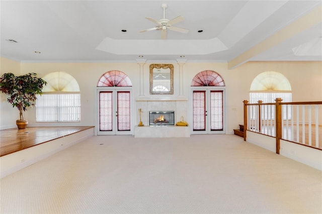 unfurnished living room with french doors, ceiling fan, a raised ceiling, and light carpet