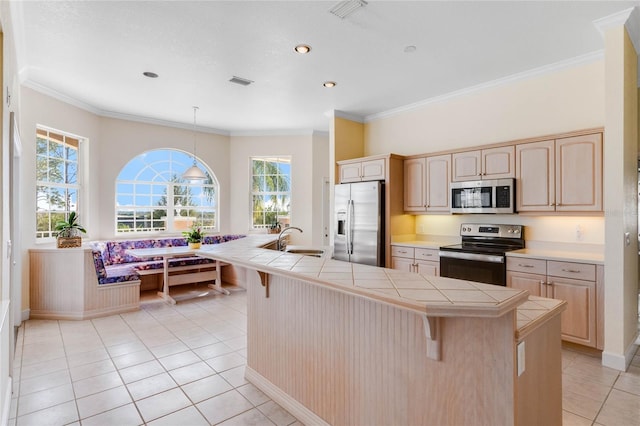 kitchen with sink, tile counters, breakfast area, stainless steel appliances, and light brown cabinets