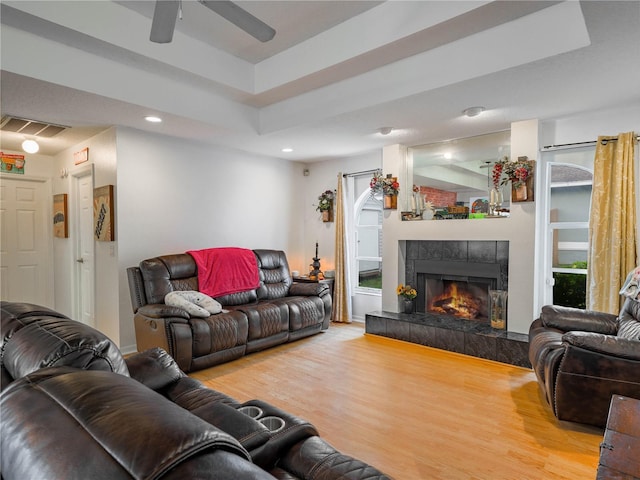 living room featuring light hardwood / wood-style floors, ceiling fan, and a tiled fireplace
