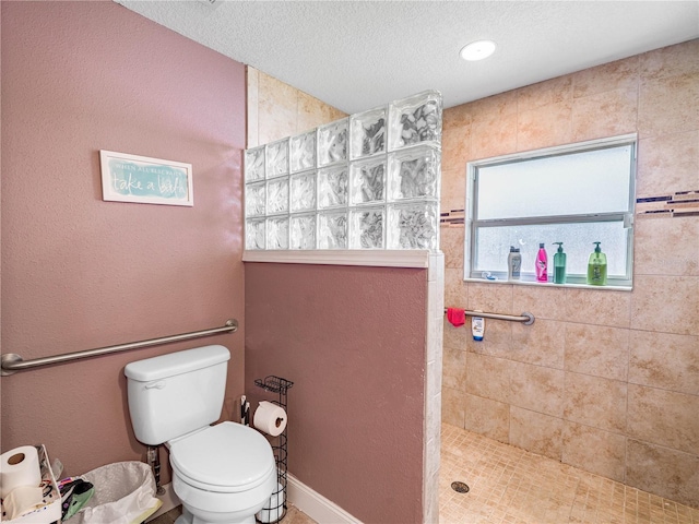 bathroom featuring plenty of natural light, toilet, a textured ceiling, and a tile shower