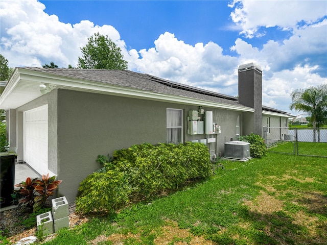 view of side of home with a lawn and central AC