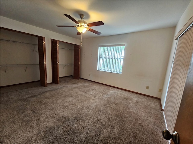 unfurnished bedroom with two closets, ceiling fan, and carpet floors