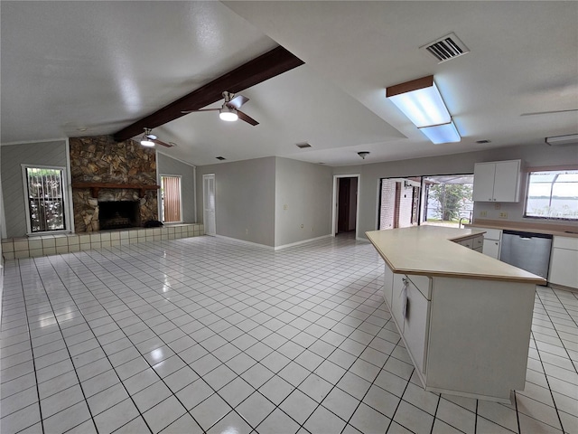 kitchen featuring dishwasher, a stone fireplace, lofted ceiling with beams, ceiling fan, and white cabinets
