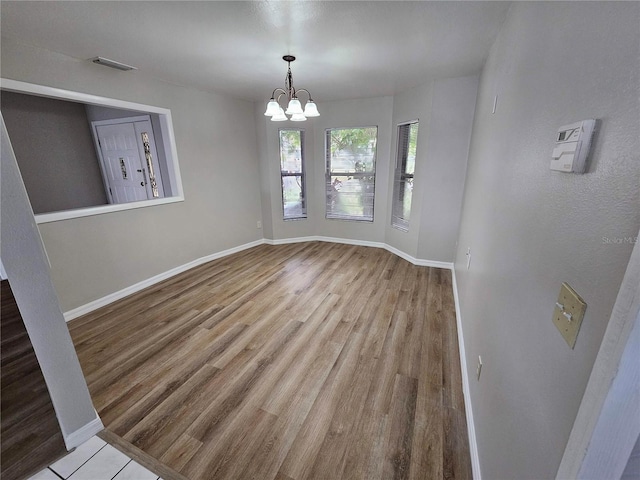 unfurnished dining area with hardwood / wood-style flooring and an inviting chandelier