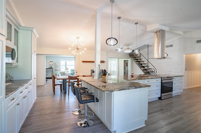 kitchen with hardwood / wood-style floors, hanging light fixtures, a notable chandelier, appliances with stainless steel finishes, and a kitchen bar