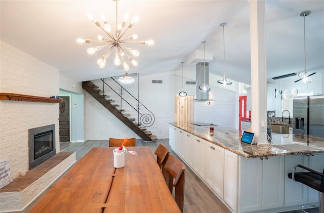 dining room featuring a notable chandelier, lofted ceiling, wood-type flooring, and sink