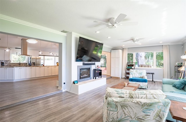 living room featuring ornamental molding, ceiling fan, and light hardwood / wood-style flooring