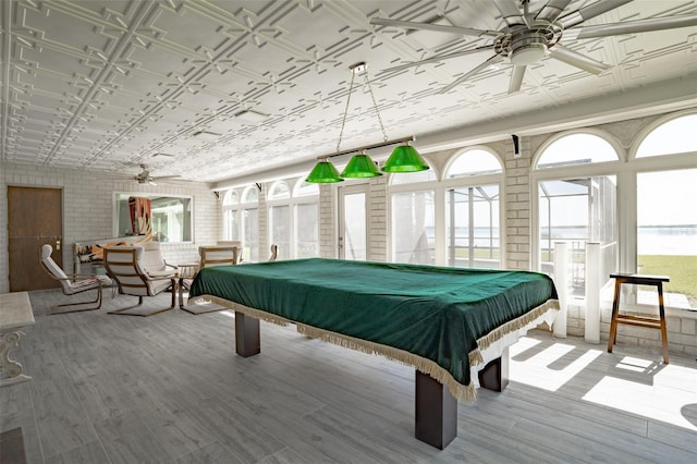 recreation room featuring brick wall, pool table, light hardwood / wood-style floors, and ceiling fan