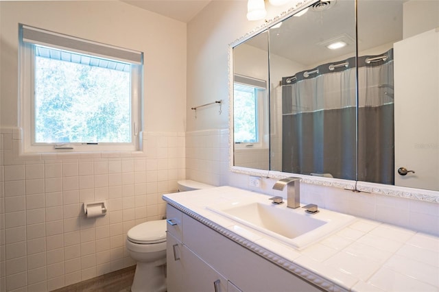 bathroom with plenty of natural light, toilet, oversized vanity, and tile walls