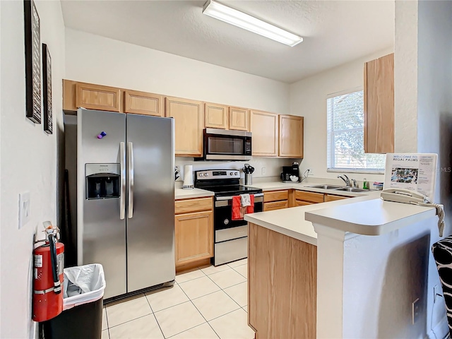 kitchen featuring light brown cabinetry, kitchen peninsula, sink, light tile floors, and appliances with stainless steel finishes