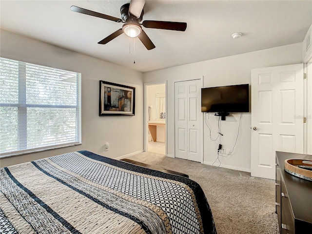 carpeted bedroom with a closet, ensuite bath, and ceiling fan