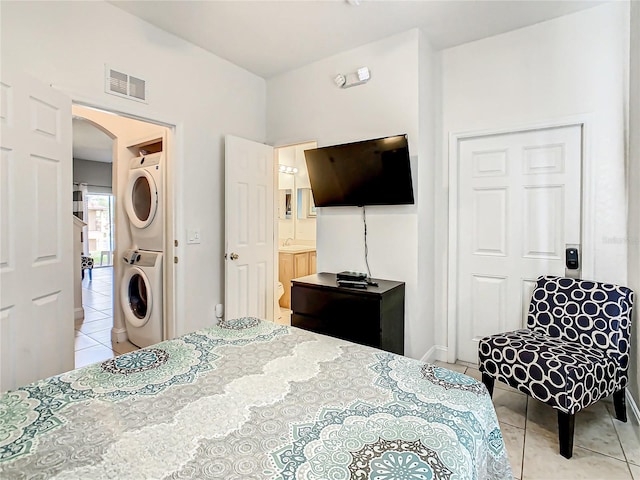 bedroom featuring sink, stacked washer / dryer, and light tile flooring