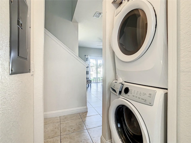 laundry room featuring light tile floors and stacked washer and dryer