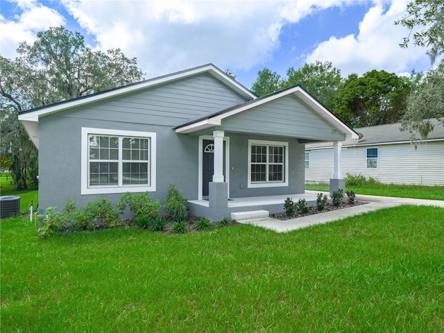 view of front facade featuring a porch, a front yard, and central AC