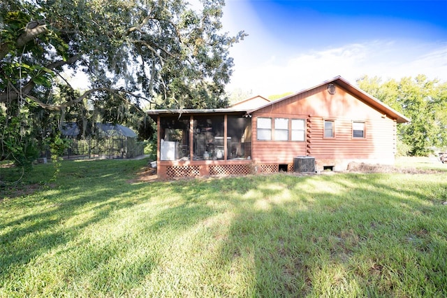 back of property featuring central air condition unit, a sunroom, and a lawn