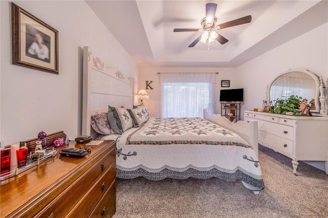 bedroom featuring carpet flooring, a tray ceiling, and ceiling fan