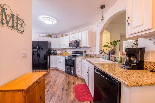 kitchen featuring sink, black appliances, pendant lighting, and white cabinets