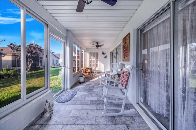 unfurnished sunroom featuring ceiling fan and plenty of natural light