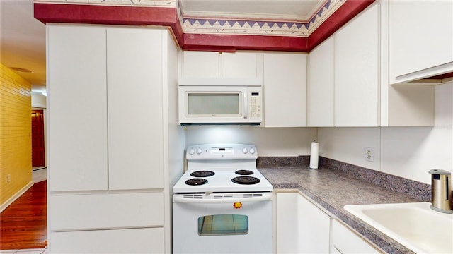 kitchen featuring hardwood / wood-style floors, sink, white appliances, and white cabinets