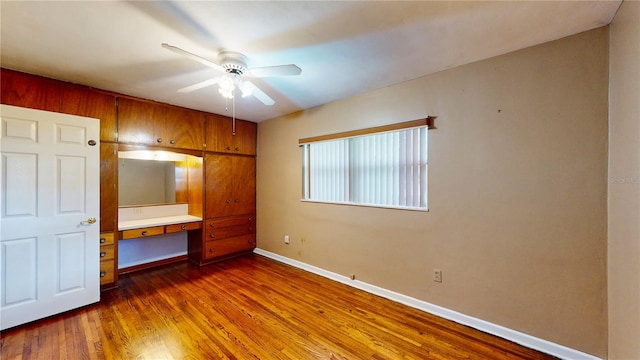 unfurnished bedroom featuring ceiling fan, dark hardwood / wood-style floors, and built in desk