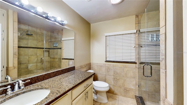 bathroom featuring vanity, tile patterned flooring, a shower with shower door, tile walls, and toilet