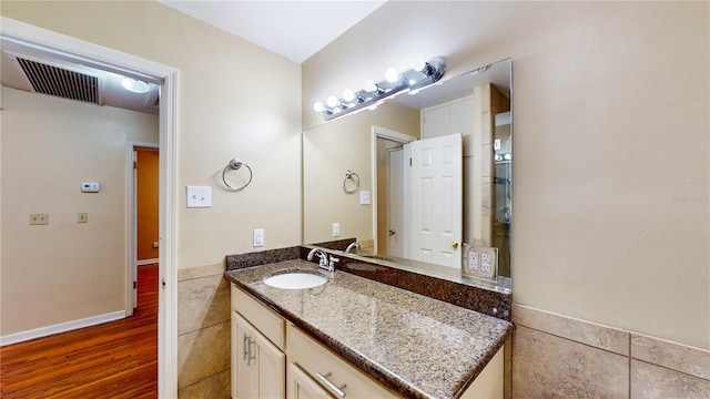 bathroom with hardwood / wood-style flooring, vanity, and tile walls