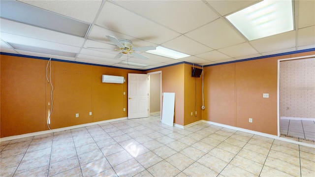 empty room with a paneled ceiling, ceiling fan, light tile patterned flooring, and a wall unit AC