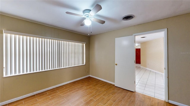 tiled empty room featuring ceiling fan and brick wall