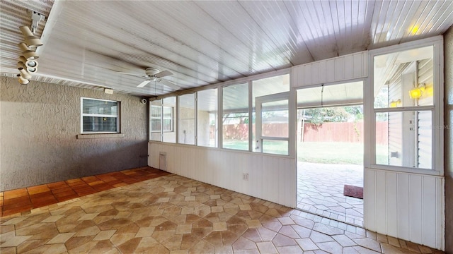 unfurnished sunroom featuring ceiling fan