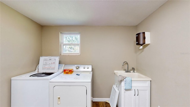 laundry area featuring washer and dryer, sink, wood-type flooring, and cabinets