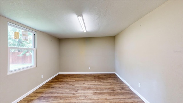 unfurnished room with a textured ceiling and light hardwood / wood-style flooring