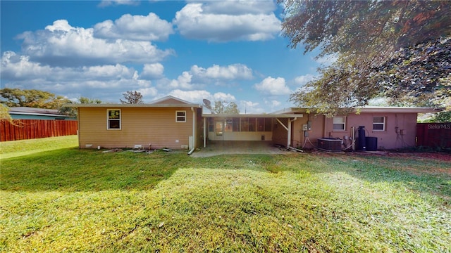 back of property with central AC unit and a yard