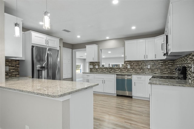 kitchen featuring decorative light fixtures, kitchen peninsula, white cabinetry, light stone countertops, and stainless steel appliances