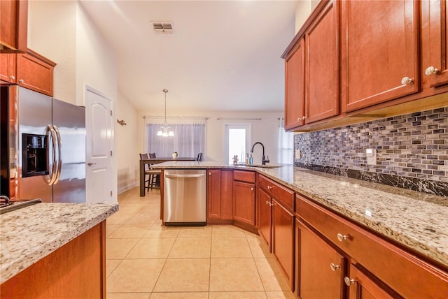 kitchen featuring light stone countertops, sink, pendant lighting, decorative backsplash, and appliances with stainless steel finishes