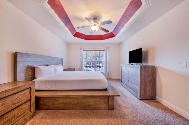 carpeted bedroom with a tray ceiling, ceiling fan, and ornamental molding