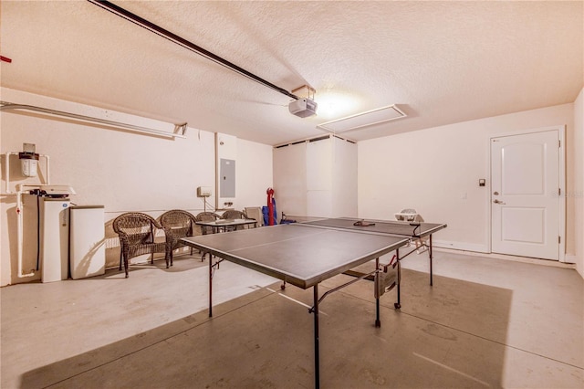 recreation room featuring concrete flooring, a textured ceiling, and electric panel