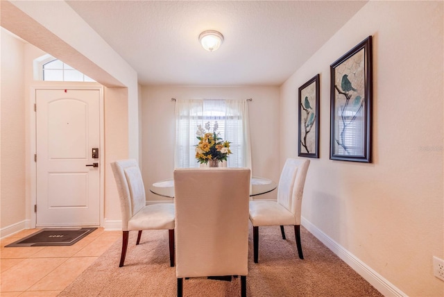 dining space featuring light tile patterned floors and baseboards