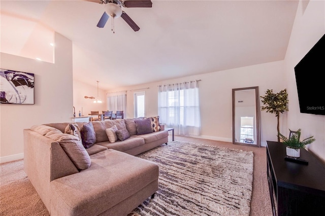 living area with baseboards, light colored carpet, vaulted ceiling, and ceiling fan with notable chandelier