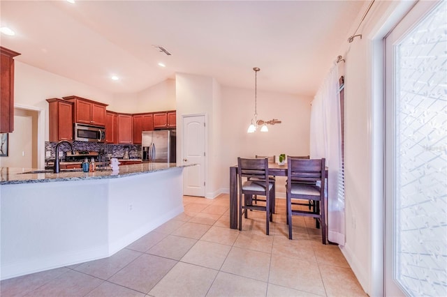 kitchen featuring visible vents, vaulted ceiling, stone counters, stainless steel appliances, and a sink