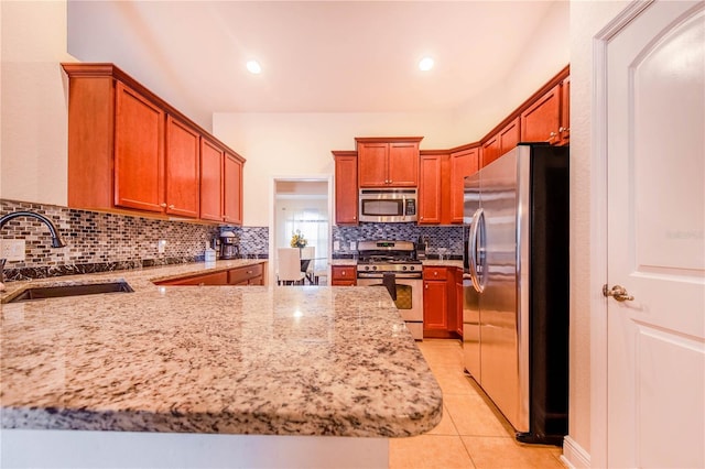 kitchen with a sink, backsplash, appliances with stainless steel finishes, light tile patterned flooring, and light stone countertops