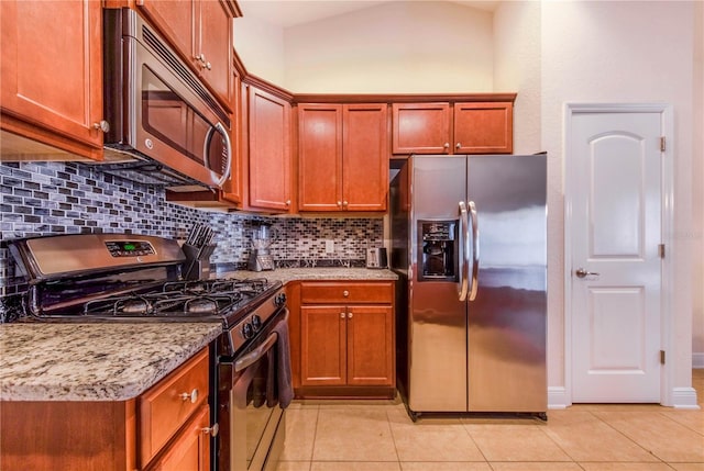kitchen with decorative backsplash, light stone counters, light tile patterned floors, and appliances with stainless steel finishes