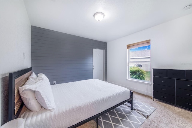 bedroom with light colored carpet, baseboards, and wood walls