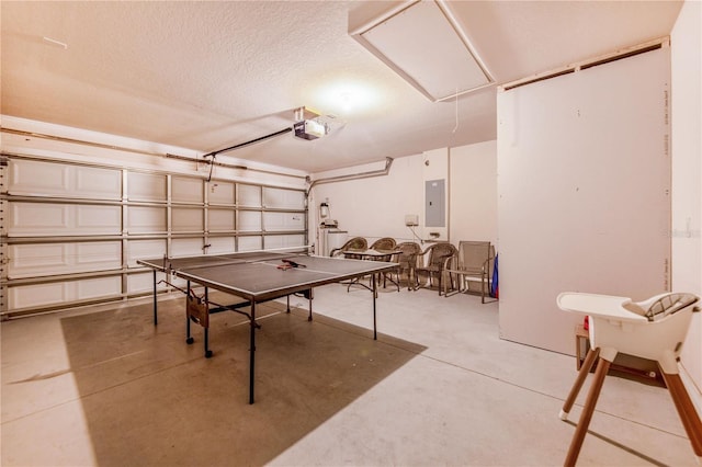 recreation room featuring concrete floors, attic access, electric panel, a garage, and a textured ceiling