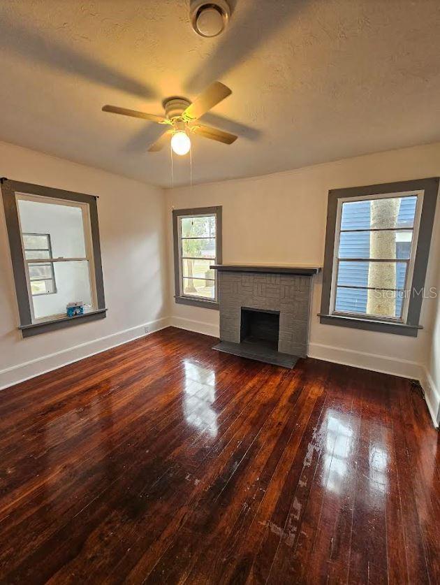 1414 Johns Ave, Haines City, FL 33844 - unfurnished living room featuring dark wood-type flooring, ceiling fan, and a fireplace