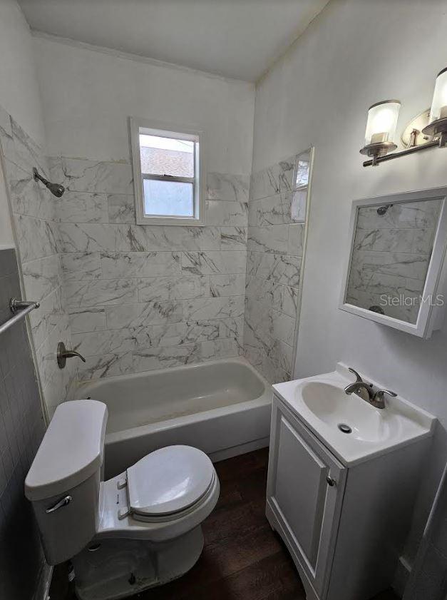 1414 Johns Ave, Haines City, FL 33844 - full bathroom with wood-type flooring, toilet, tiled shower / bath combo, and vanity