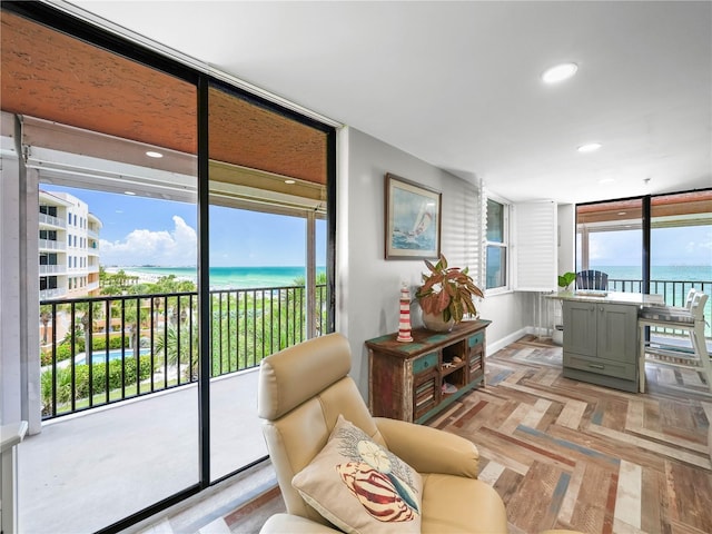 living room with light parquet flooring, a water view, and a healthy amount of sunlight