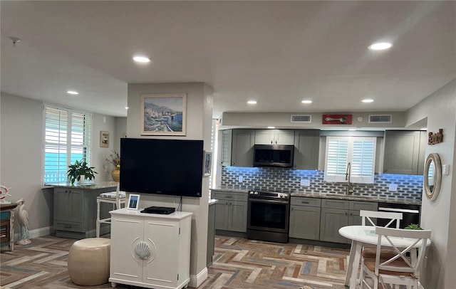 kitchen featuring appliances with stainless steel finishes, gray cabinetry, decorative backsplash, light parquet flooring, and sink