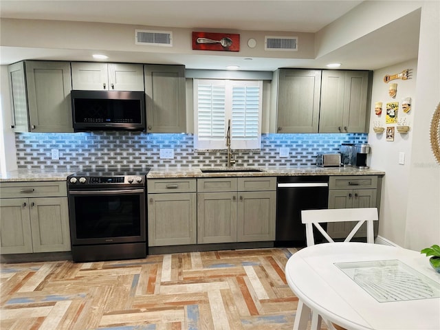 kitchen with stainless steel appliances, gray cabinetry, backsplash, light stone counters, and sink